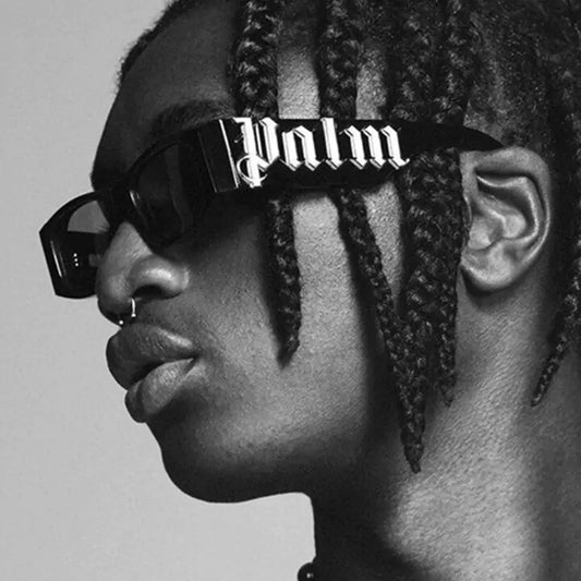 A person wearing black sunglasses with the brand name 'Palm' written across the front in white letters.